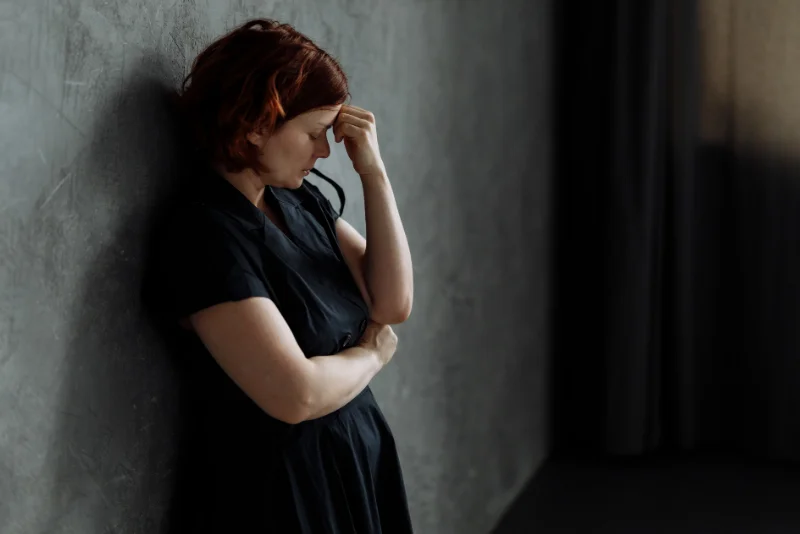 Woman pressing her hand to her forehead in distress