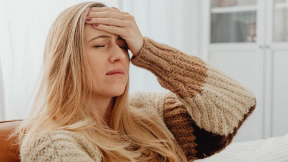 Woman holding her forehead with a headache at home