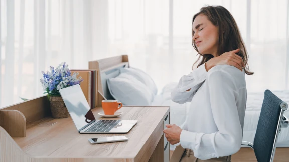 Woman experiencing shoulder pain while working at a desk